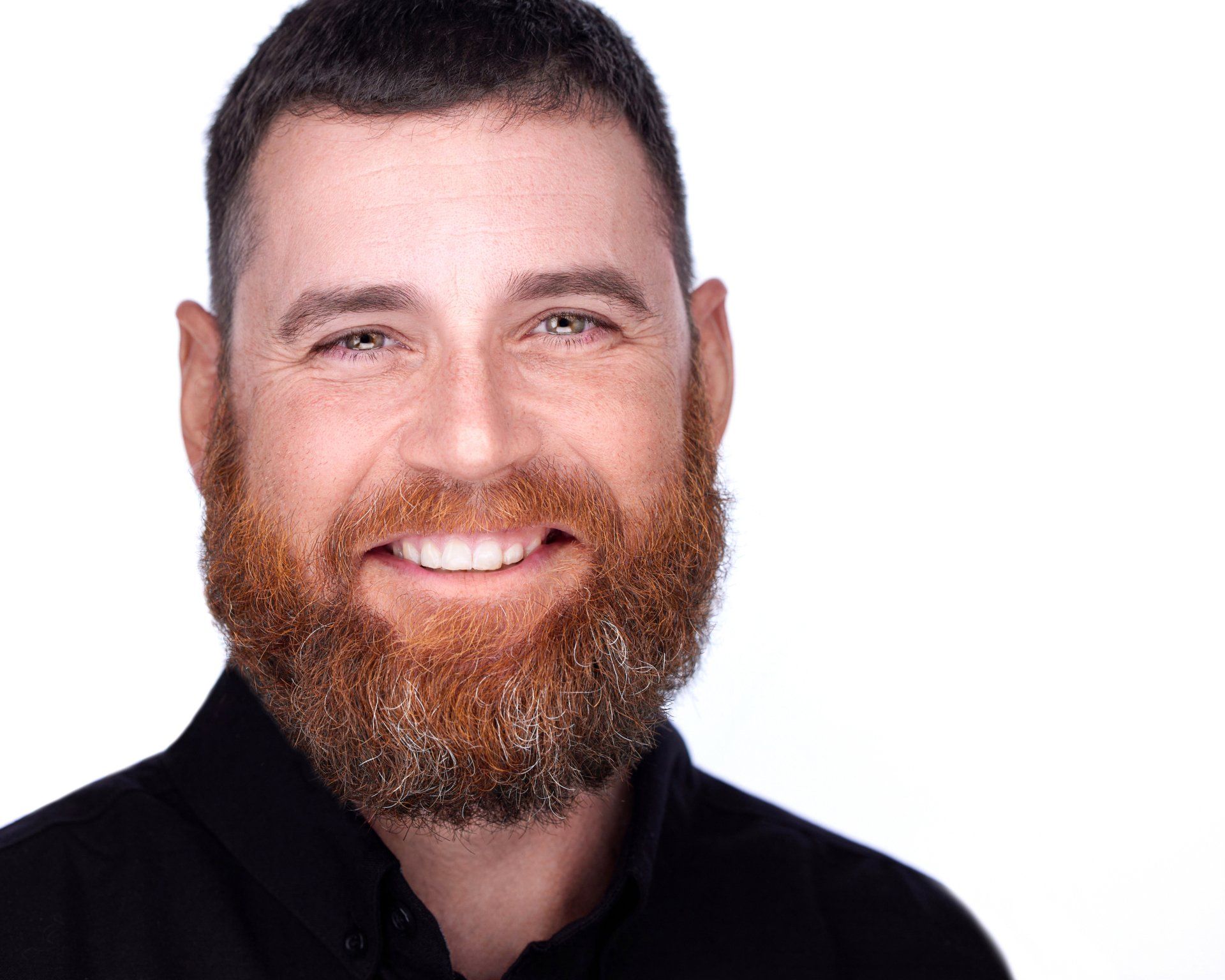A man with a beard is smiling and wearing a black shirt.