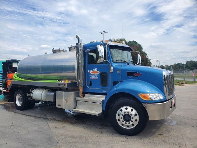 Blue septic service truck with silver tank parked outside on a sunny day.