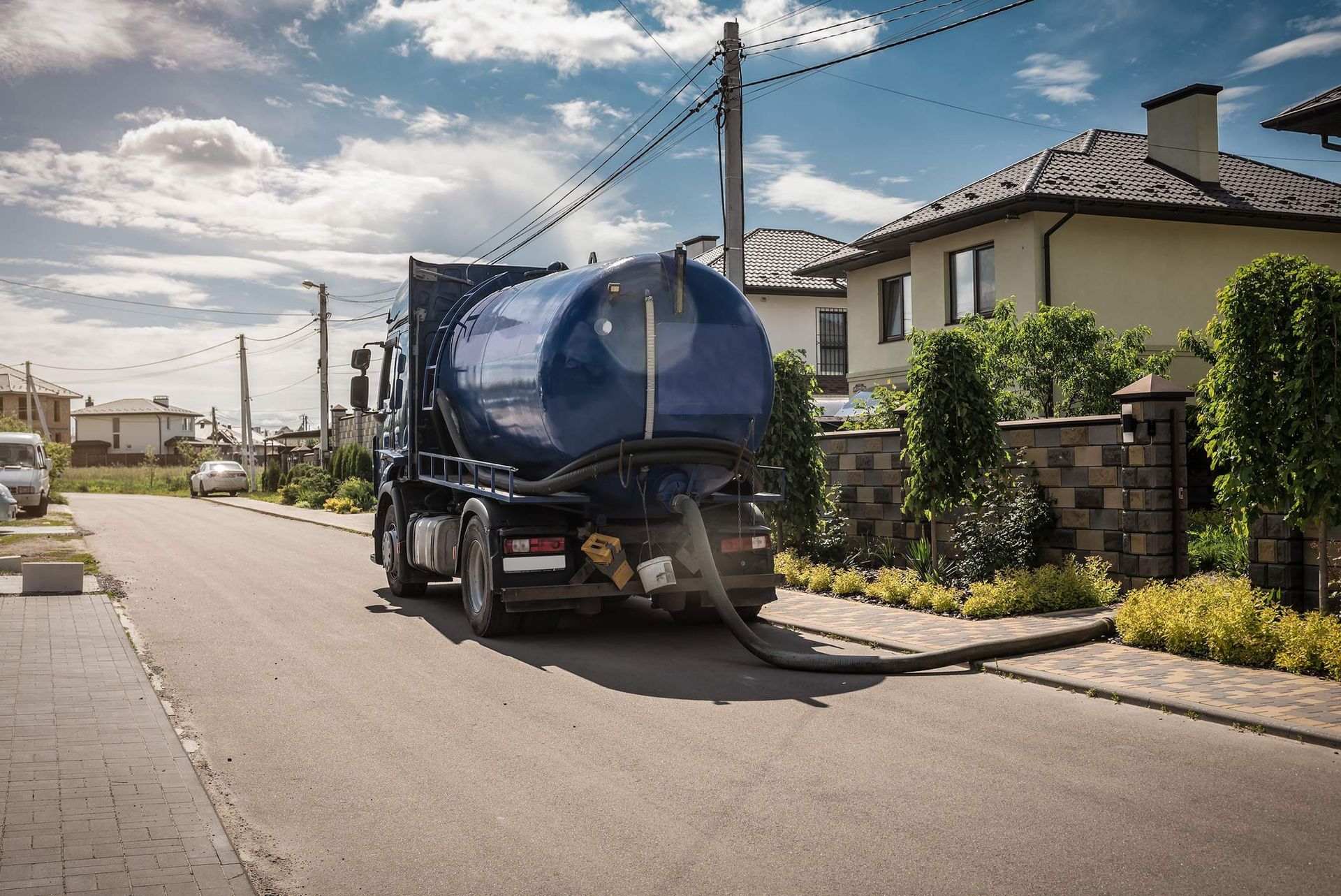 The back of a blue septic truck pumping on a residential street. The back of a blue septic truck pumping on a residential street.