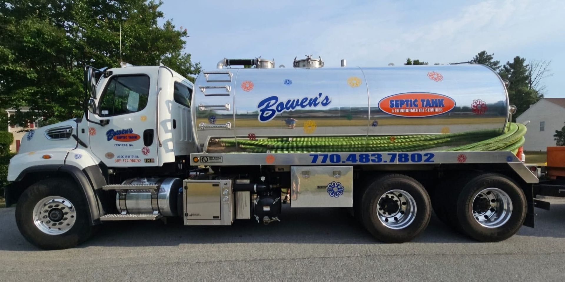 White tanker truck with blue and orange company logos parked outdoors on a street