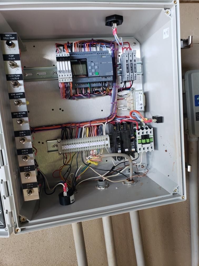 Electrical control panel with wires, Siemens PLC, and various components inside a gray enclosure.