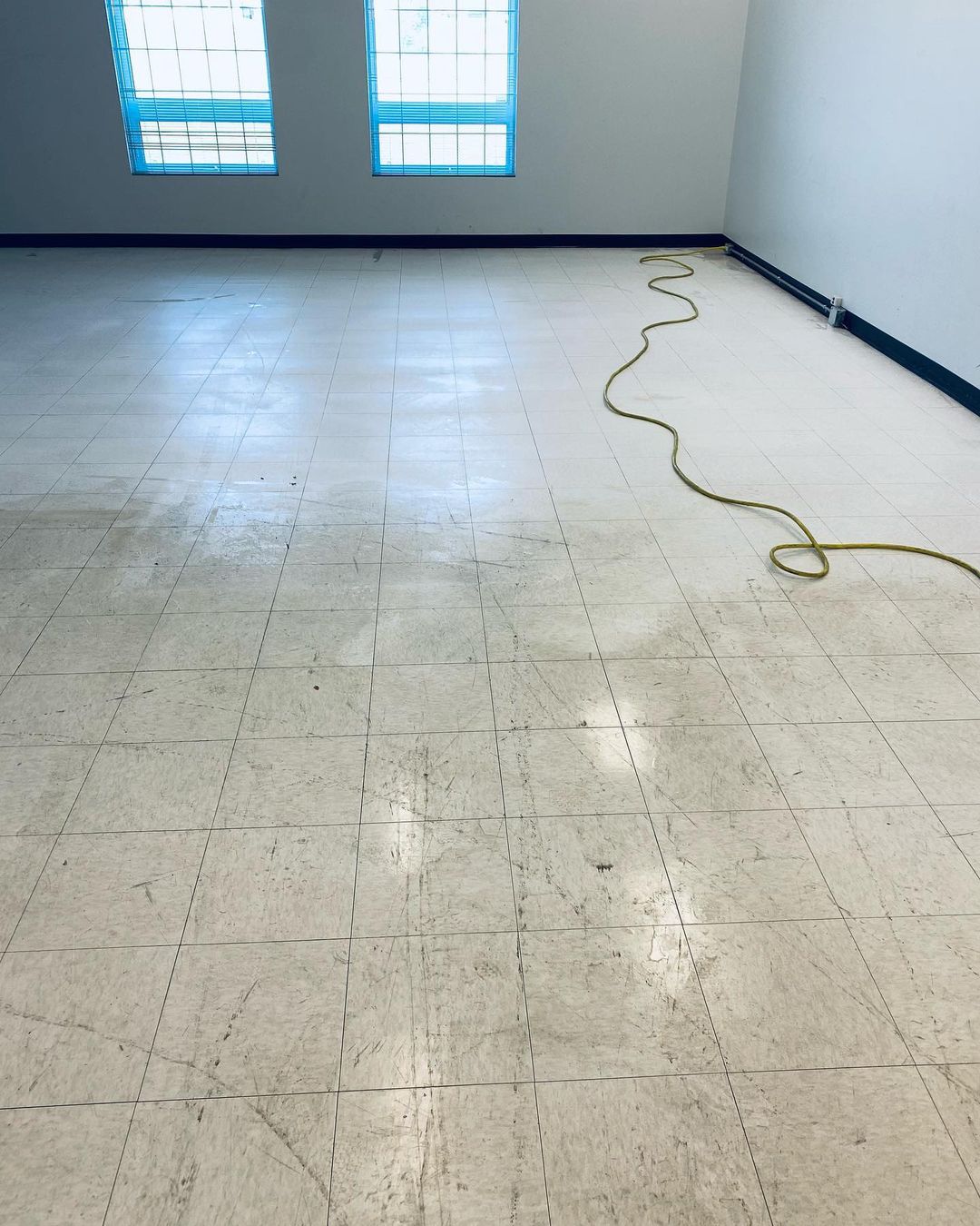 Une pièce avec un sol carrelé et deux fenêtres