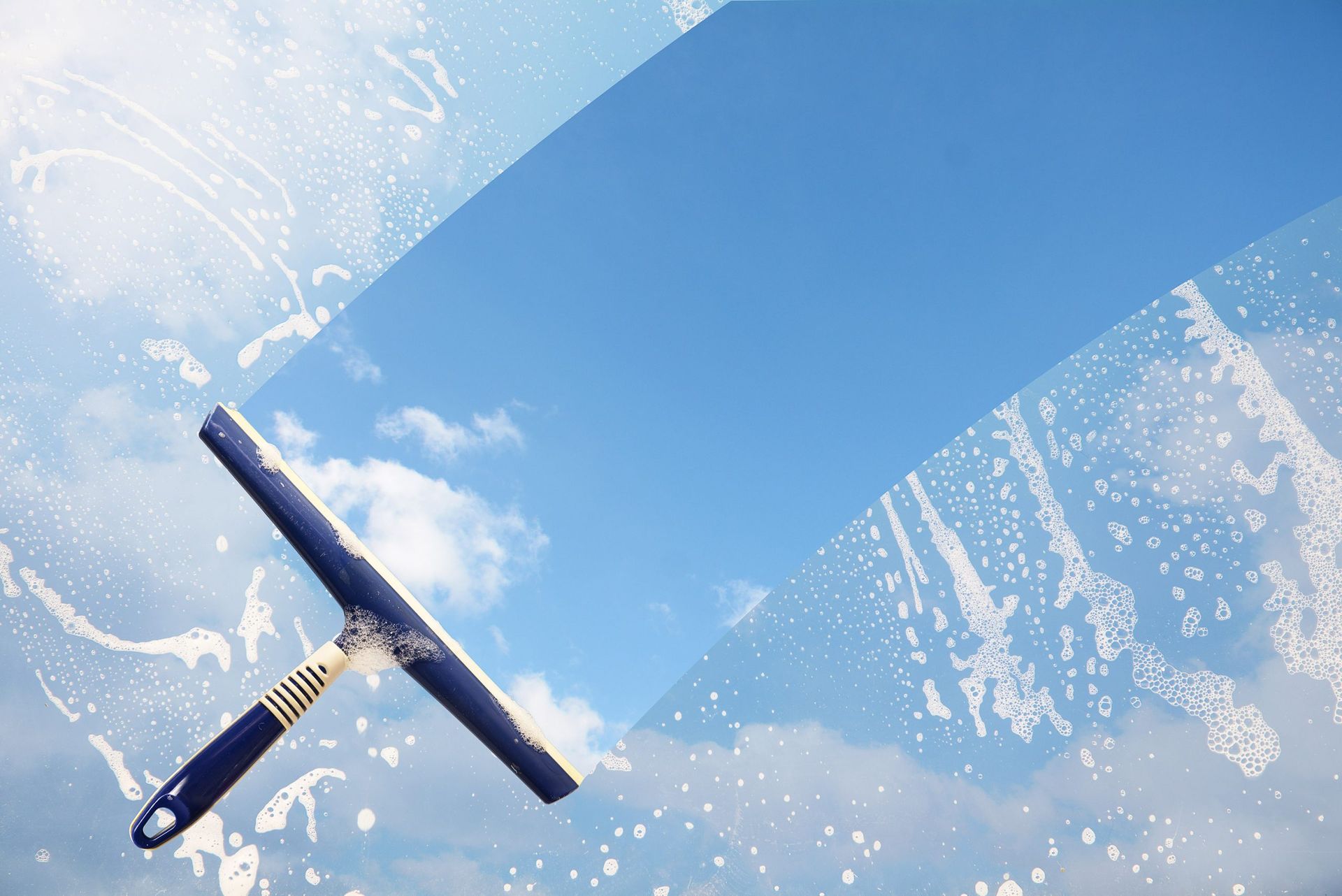 Un nettoyeur de vitres nettoie une fenêtre avec un ciel bleu en arrière-plan.