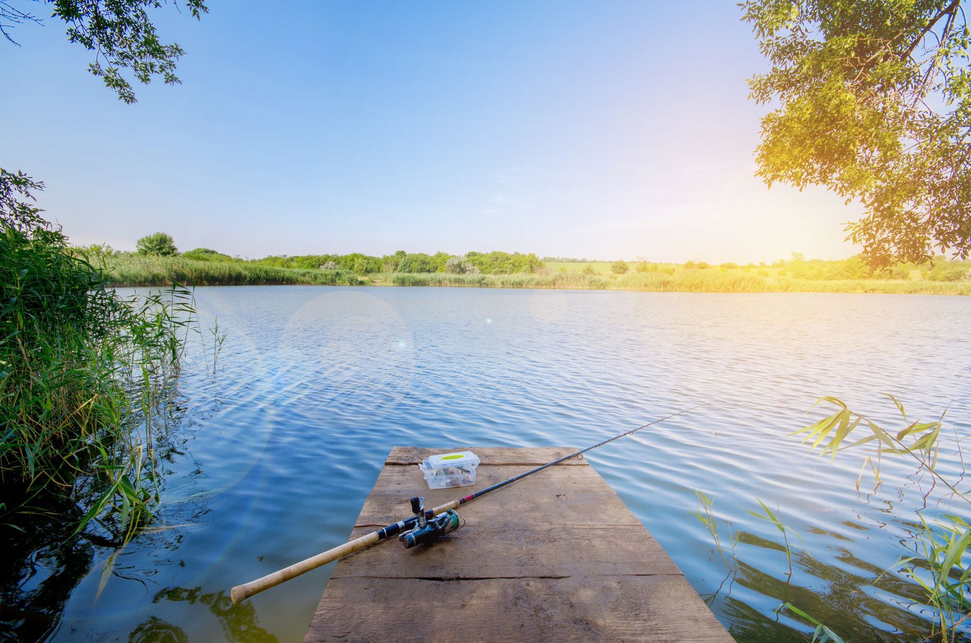 A fishing rod is sitting on a dock next to a lake.