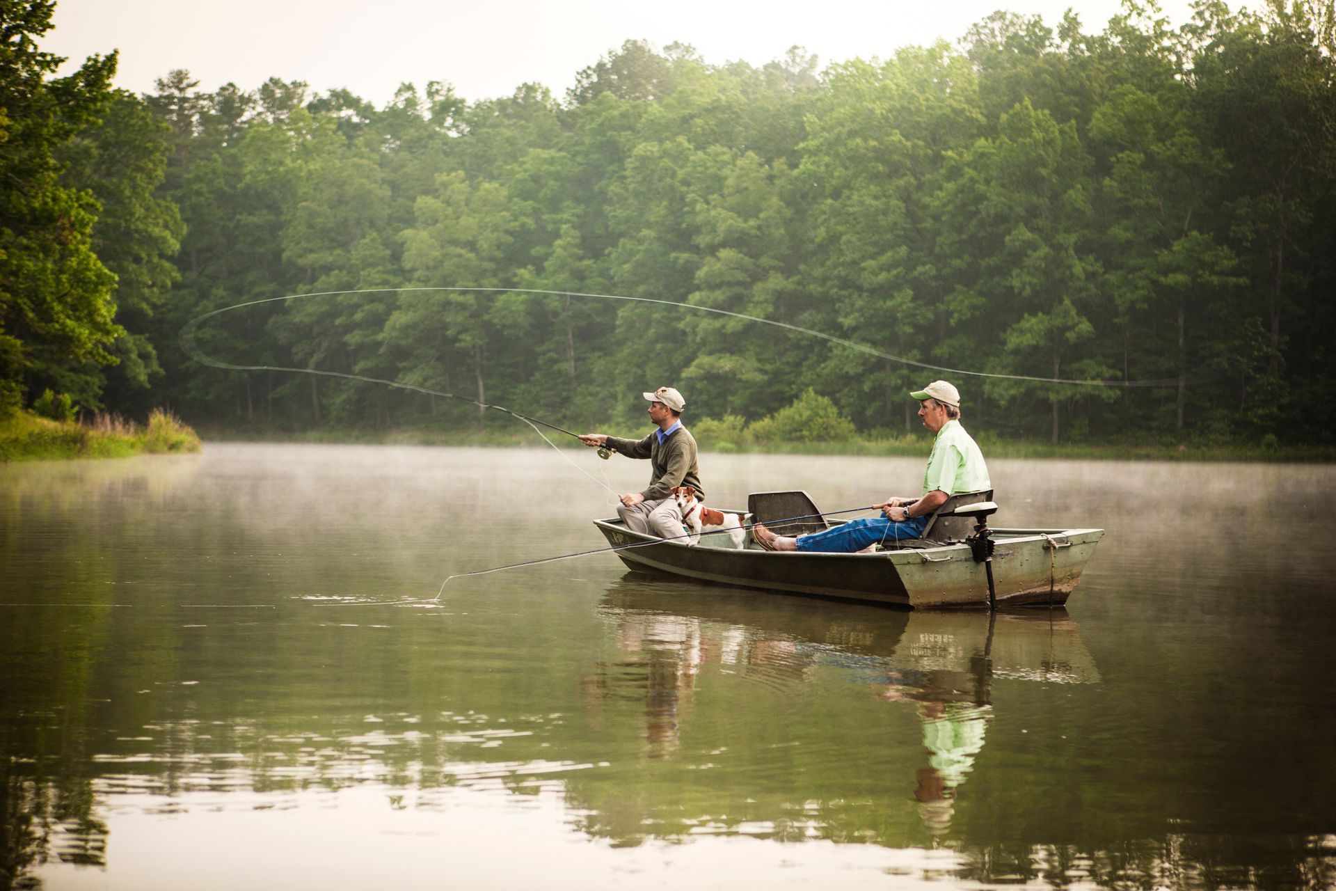Two men are fishing in a boat on a lake.