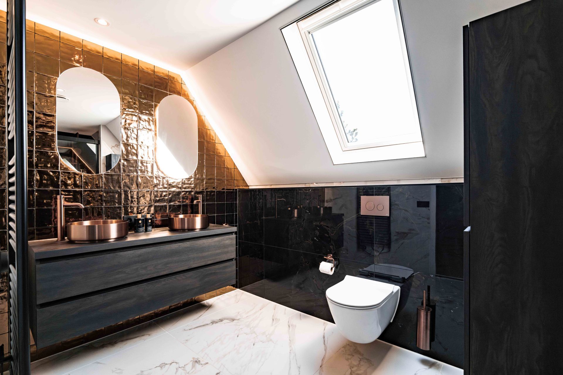 Moderne zwart-witte badkamer met dakraam, dubbele wastafel, ronde spiegels en toilet onder een schuin plafond.