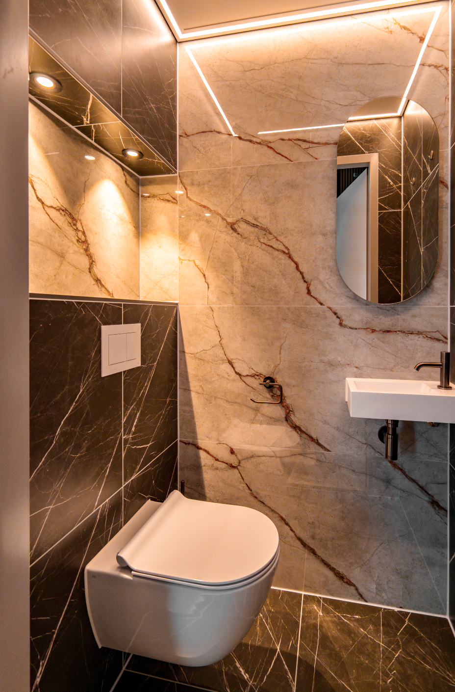 Moderne badkamer met wandtoilet, marmeren wanden, wastafel en sfeervolle inbouwverlichting.