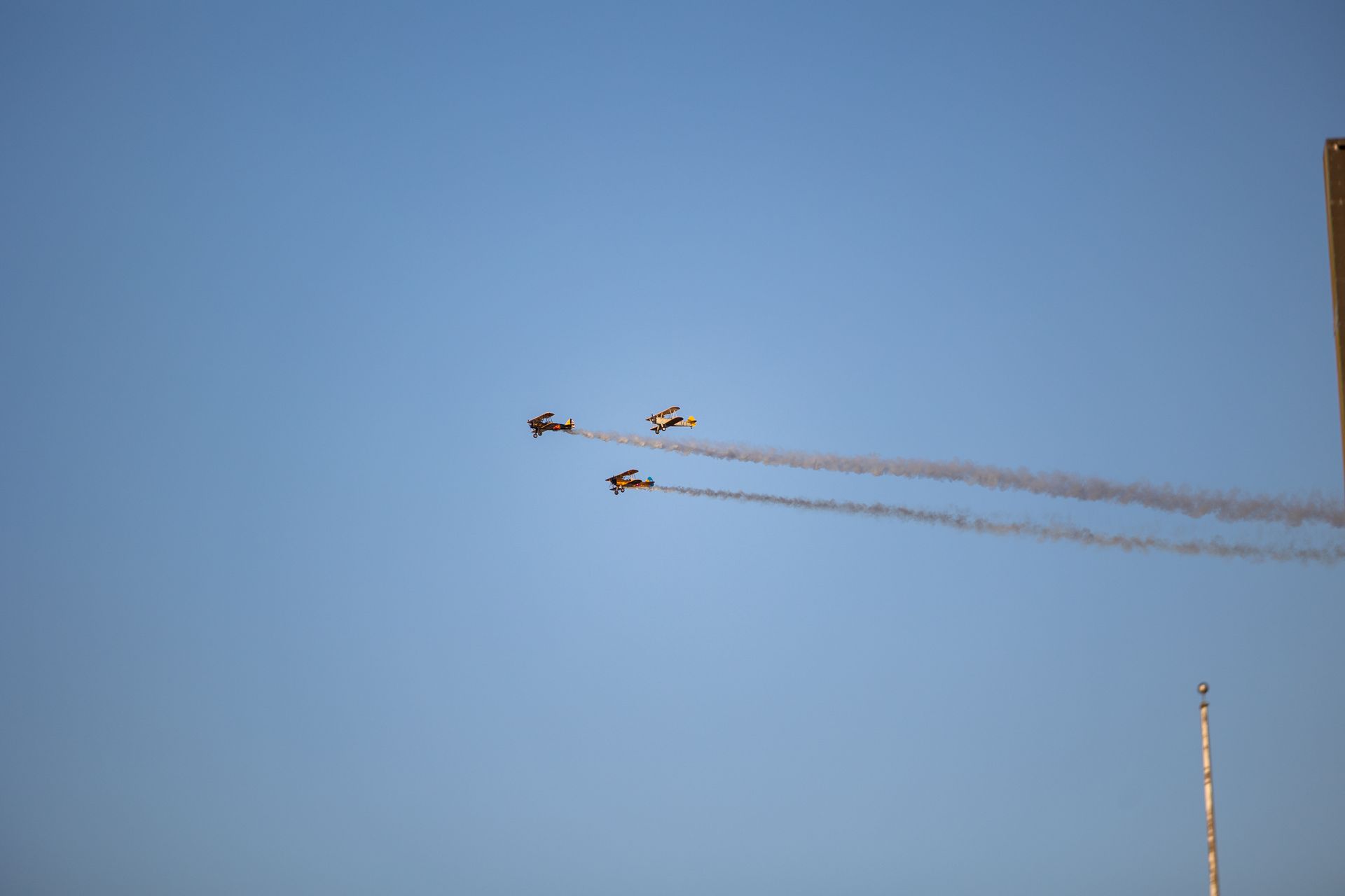 Three jets leaving smoke trails in a blue sky during an aerial display