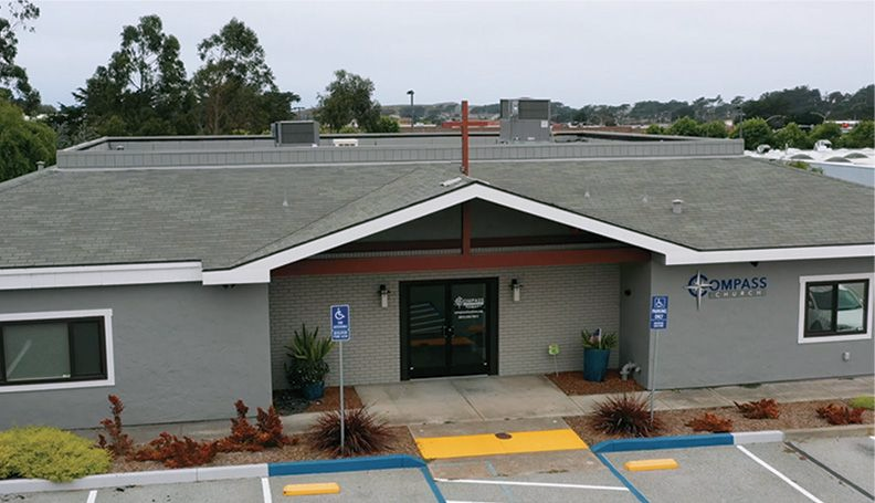 Gray building with blue accessibility parking. Compass Health Center signage above the entrance.