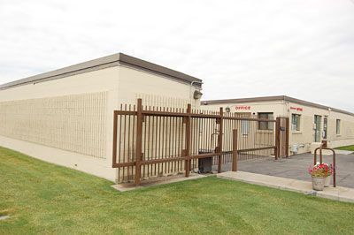 Beige building with fenced entrance ramp and walkway, grass lawn in front