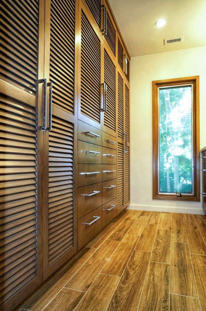 Modern closet hallway with wood louvered doors, warm lighting, and a tall window.
