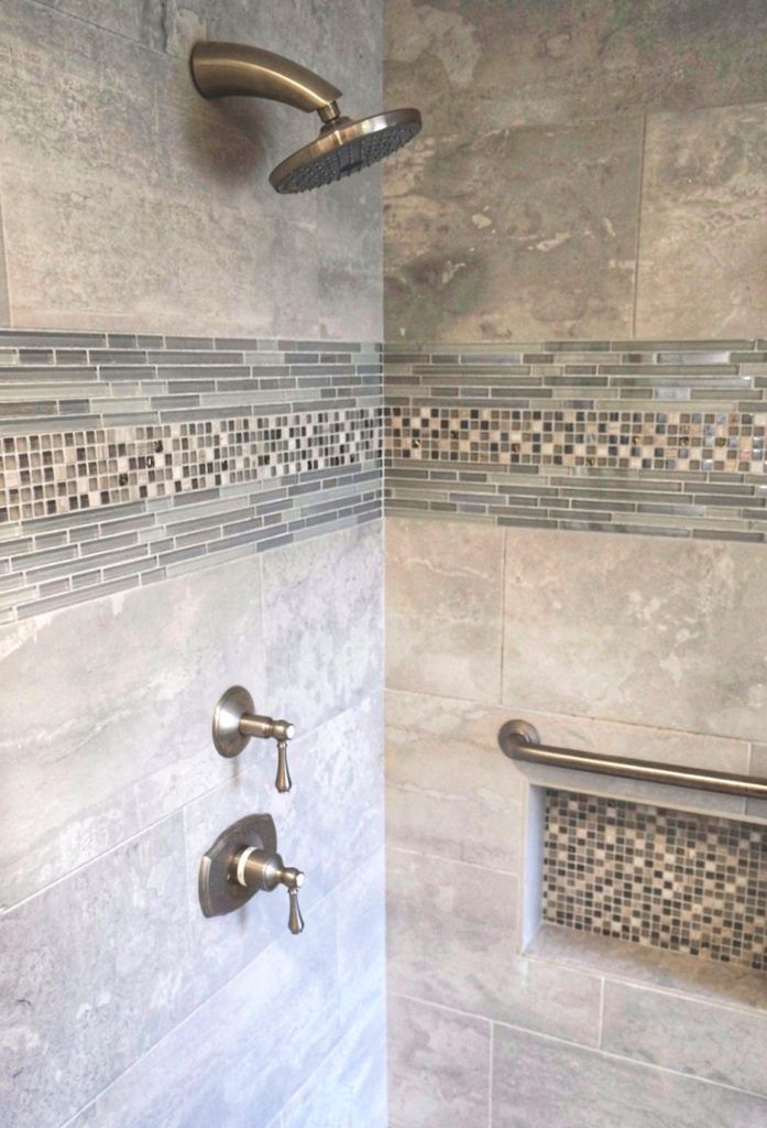 Bathroom shower with gray tile walls, mosaic accent band, and chrome fixtures and grab bar