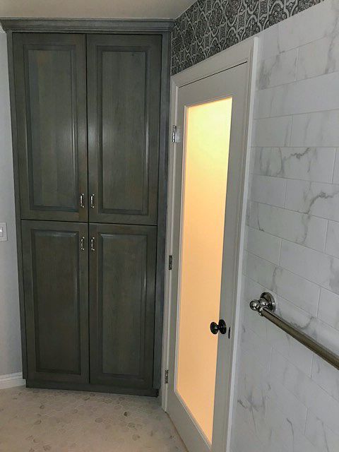 Bathroom with dark cabinets, a frosted glass door, and light gray marble-patterned walls.
