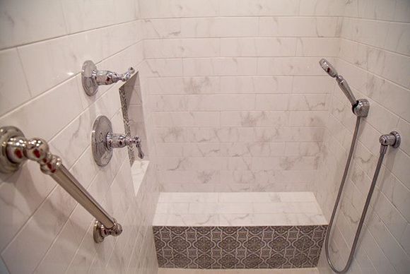 Accessible shower stall with multiple grab bars and a tiled bench seat