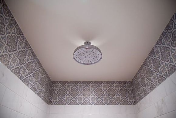 Bathroom shower with a round ceiling-mounted showerhead and patterned tile walls
