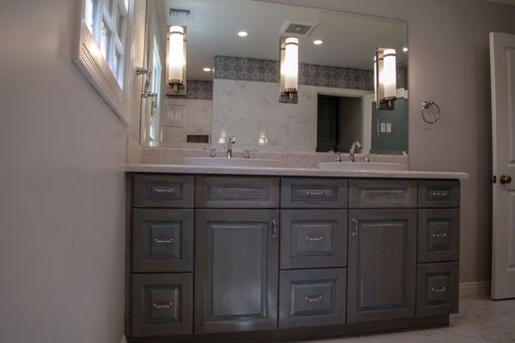 Modern bathroom vanity with dark wood cabinets, double sinks, and large mirror under pendant lights