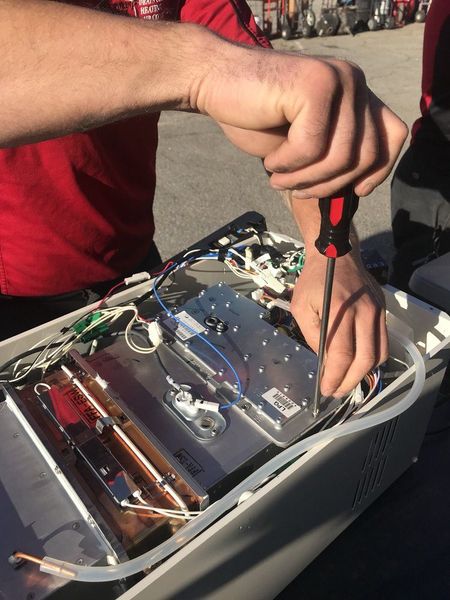 Person using a screwdriver to repair the open inside of a printer or copier