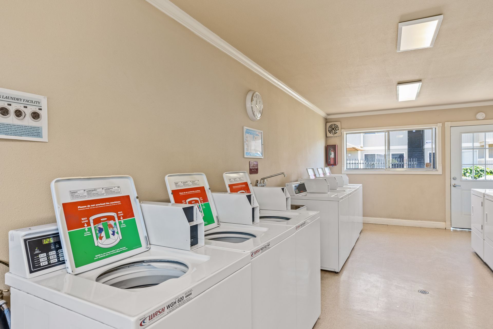Laundry room with several white washing machines.