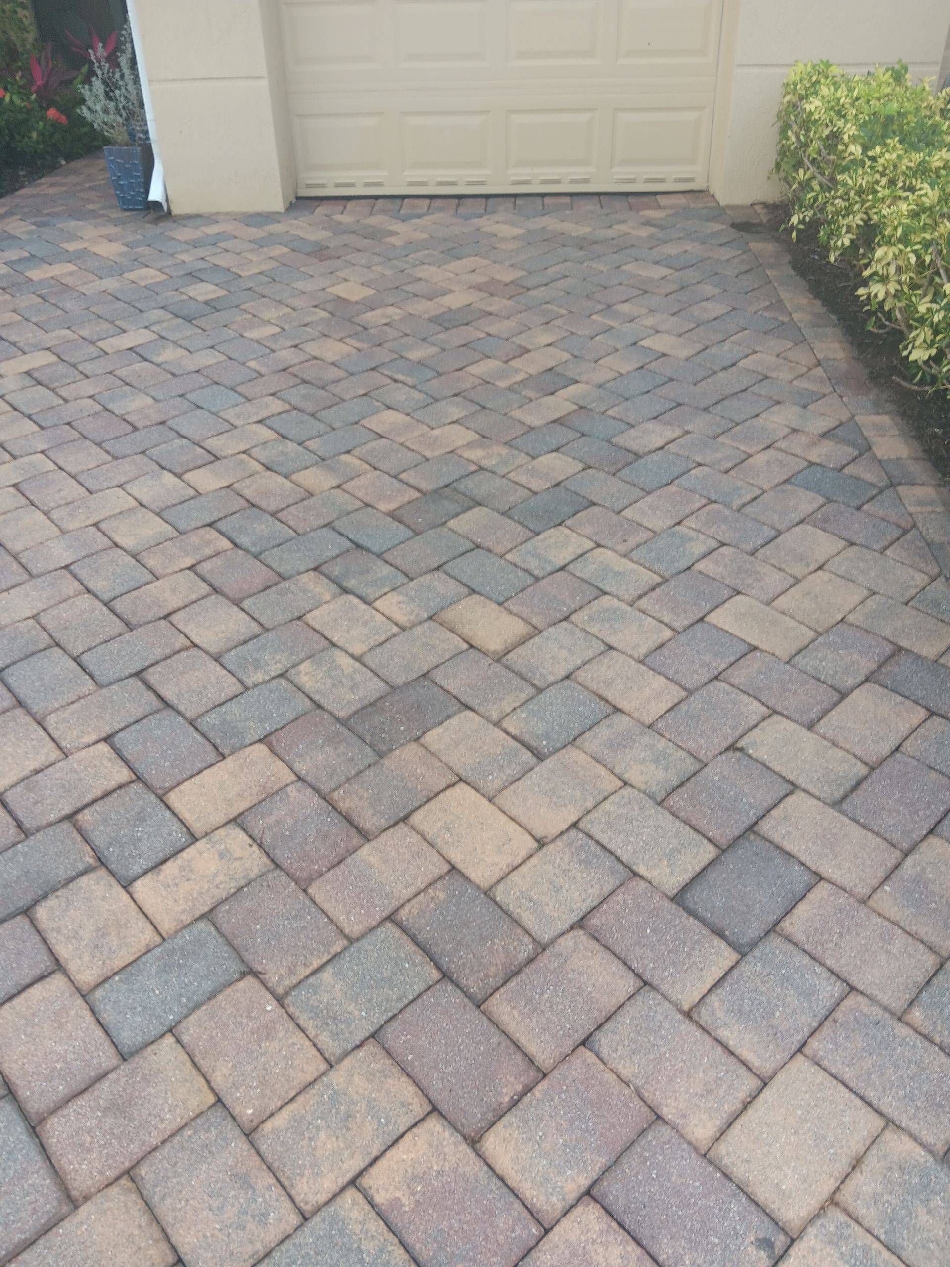A brick driveway with a garage door in the background