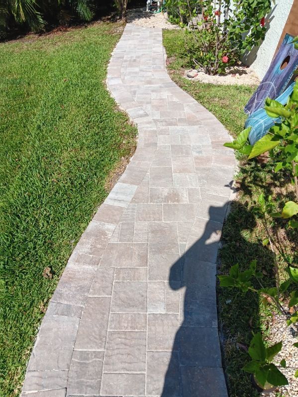 A brick walkway going through a lush green yard