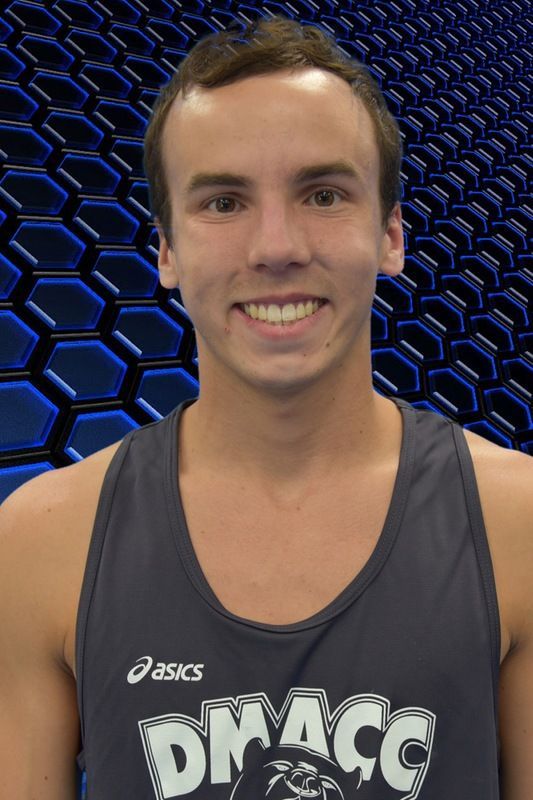 Smiling athlete in a gray tank top against a blue hexagon-patterned background