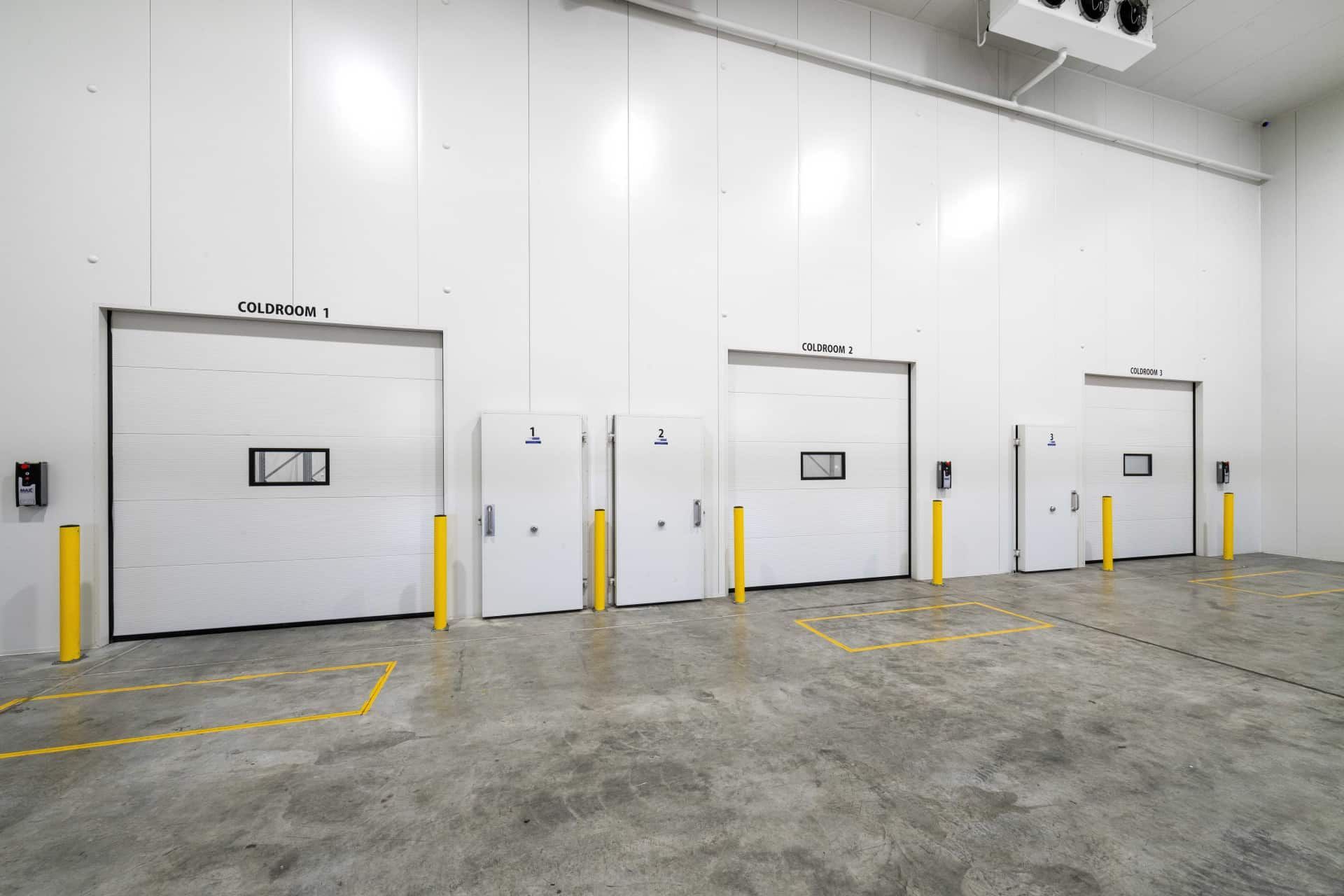 A Row of White Doors in a Warehouse With Yellow Poles — Refrigerated Technologies (QLD) Pty Ltd In Bowen, QLD