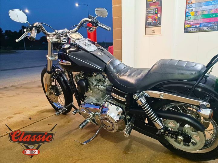 A black harley davidson motorcycle is parked in a self service car wash bay