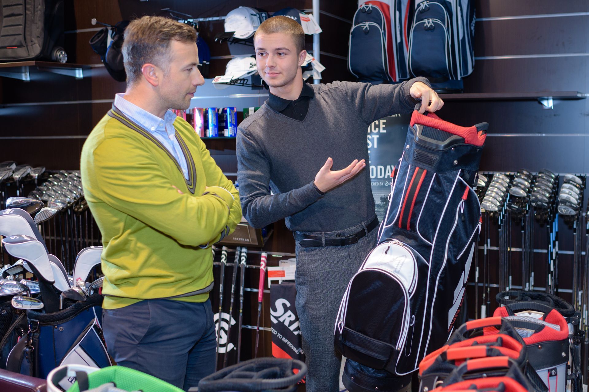 Customer reviewing a golf bag with a retail associate in a golf shop.