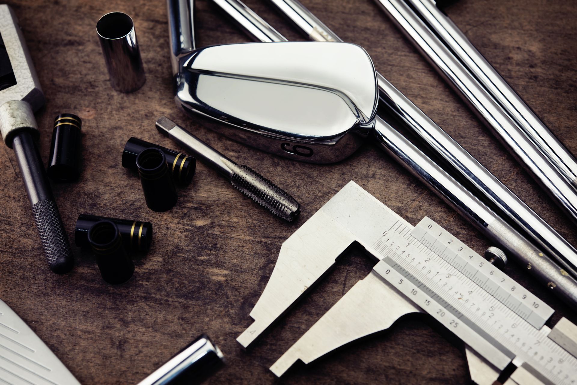 Assorted metalworking tools and parts on a workbench, including calipers and polished metal pieces.