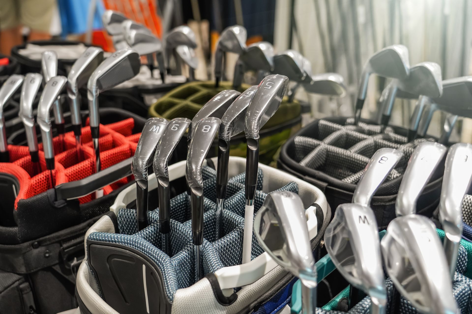Rows of numbered golf club irons displayed in golf bags at a shop