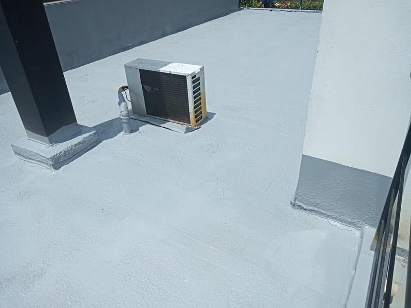Techo pintado de color gris con equipo de aire acondicionado y dos pilares.