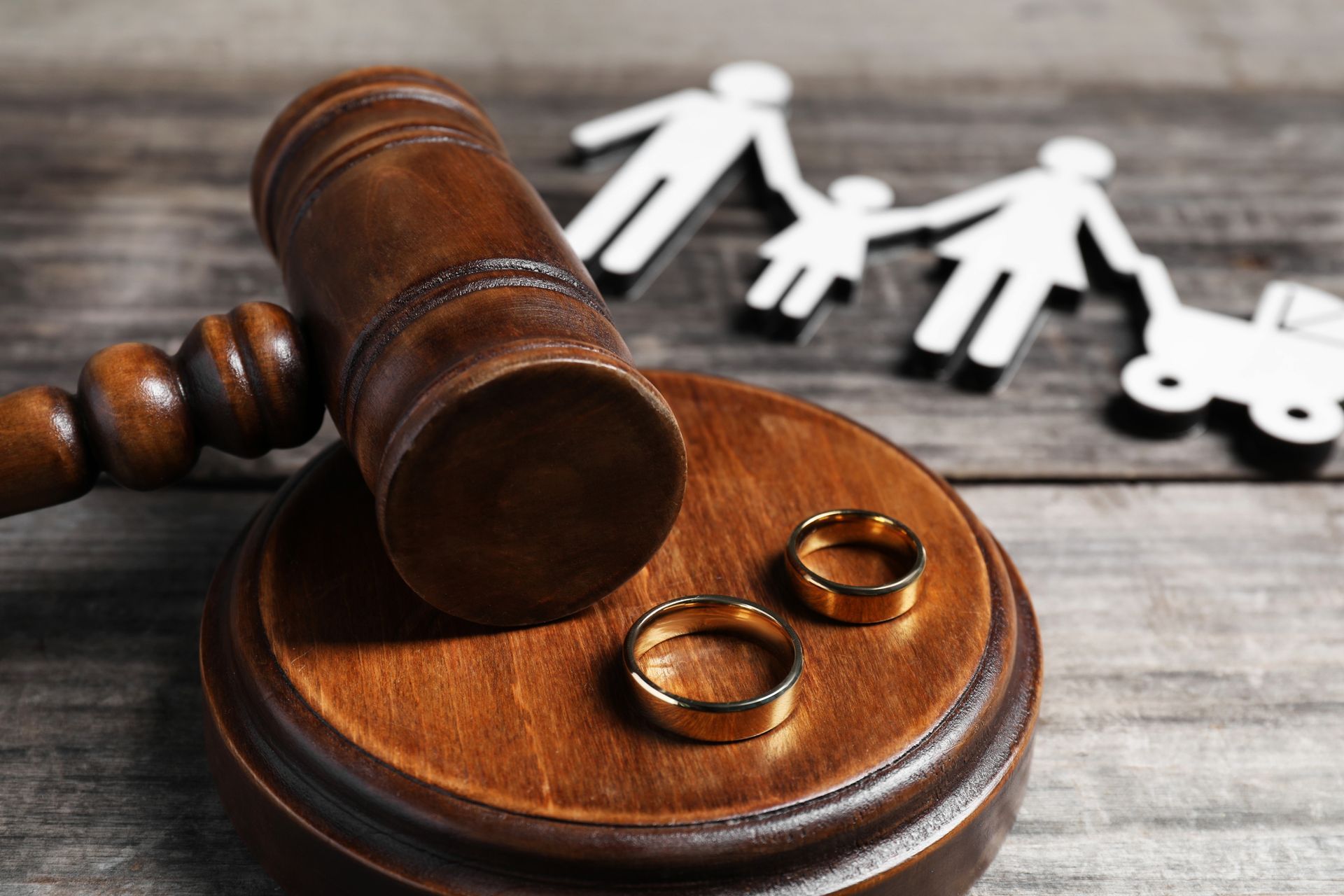 A wooden gavel with two wedding rings on top of it.