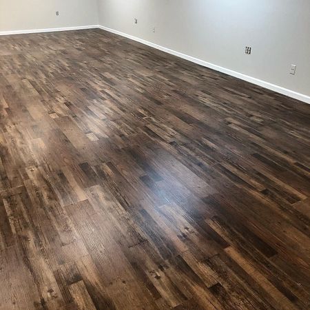 Empty room with glossy brown wood flooring and white walls.