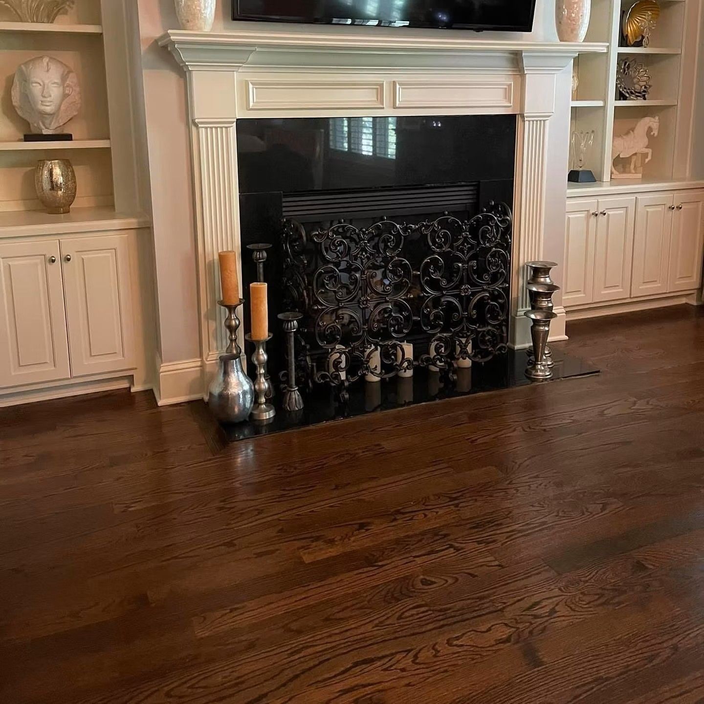 Living room fireplace with white mantel, built-in shelves, and dark hardwood floors