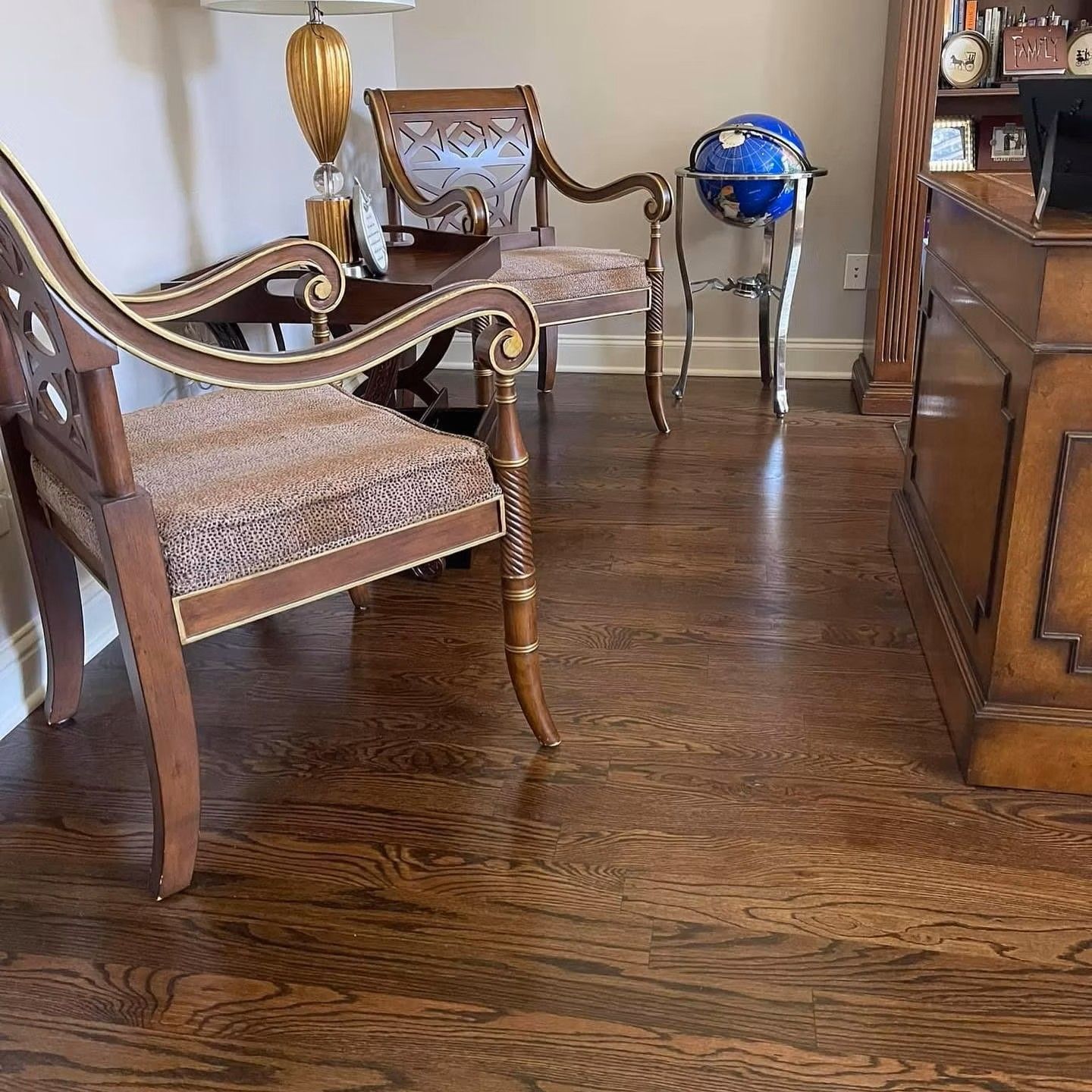 Elegant living room with carved wooden chairs, globe stand, and dark hardwood floor