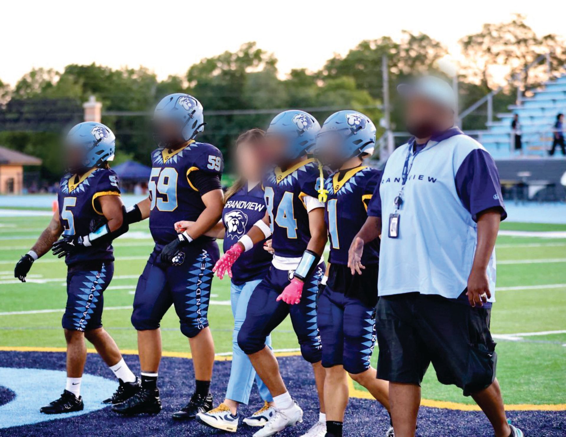 High school football players and a coach stand on the field in Liddle's uniforms.