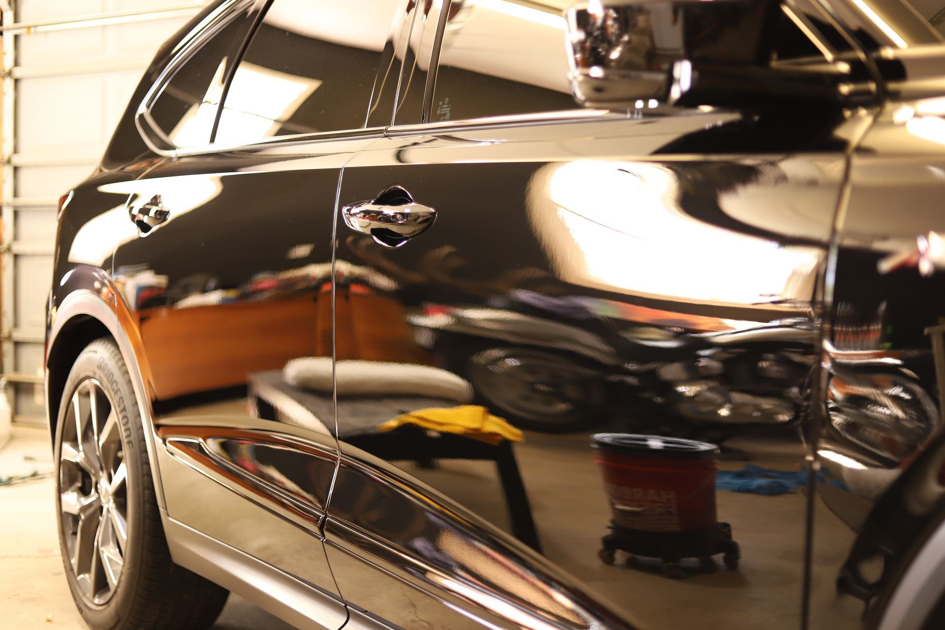 Black car with a glossy finish reflecting objects in a garage.