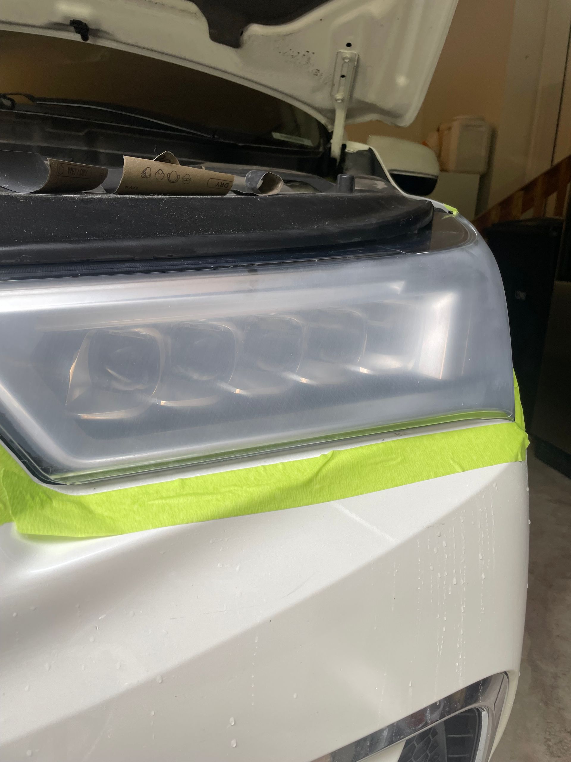 White car headlight taped off for restoration.