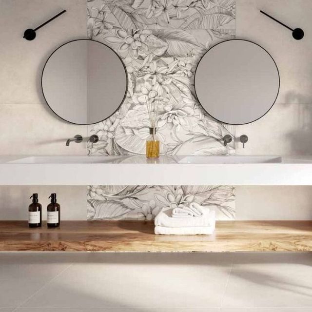 Bagno con doppi lavandini, specchi rotondi, paraschizzi con piastrelle floreali, mensola in legno e oggetti decorativi.