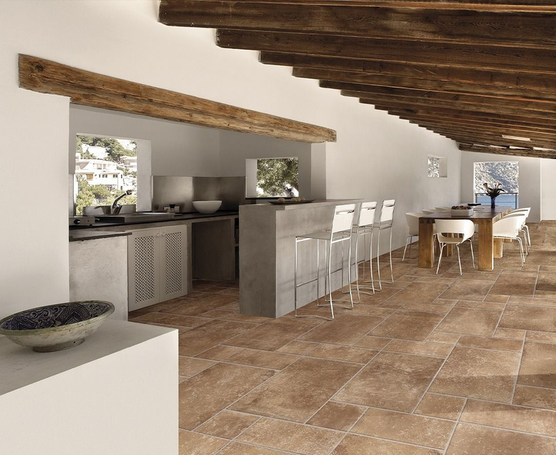 Ampia cucina con pavimenti in cotto, pareti bianche e travi in ​​legno al soffitto.