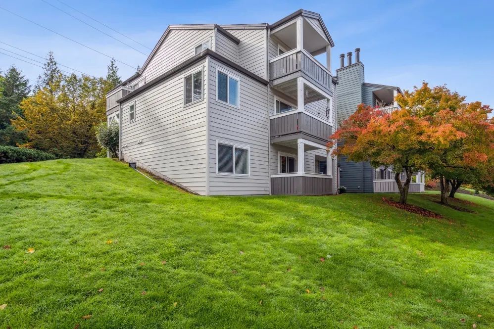 Multi-story residential building on a grassy hill; fall foliage trees with orange and red leaves.