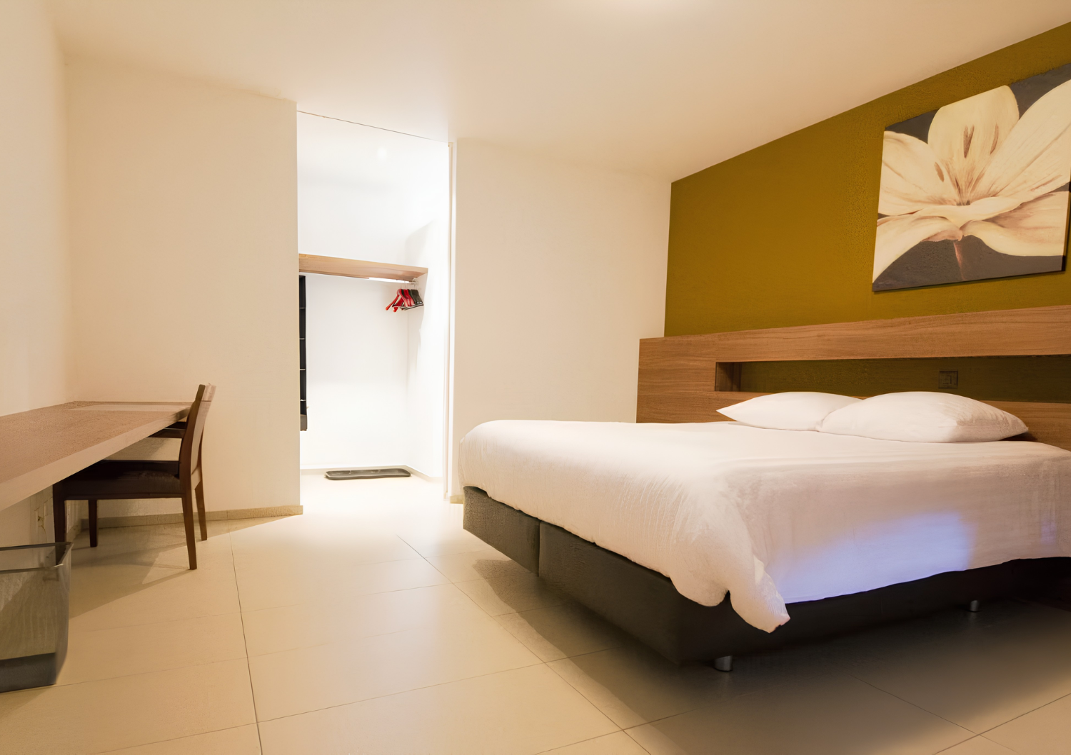 Chambre d'hôtel moderne avec lit, bureau et éclairage lumineux à l'entrée.