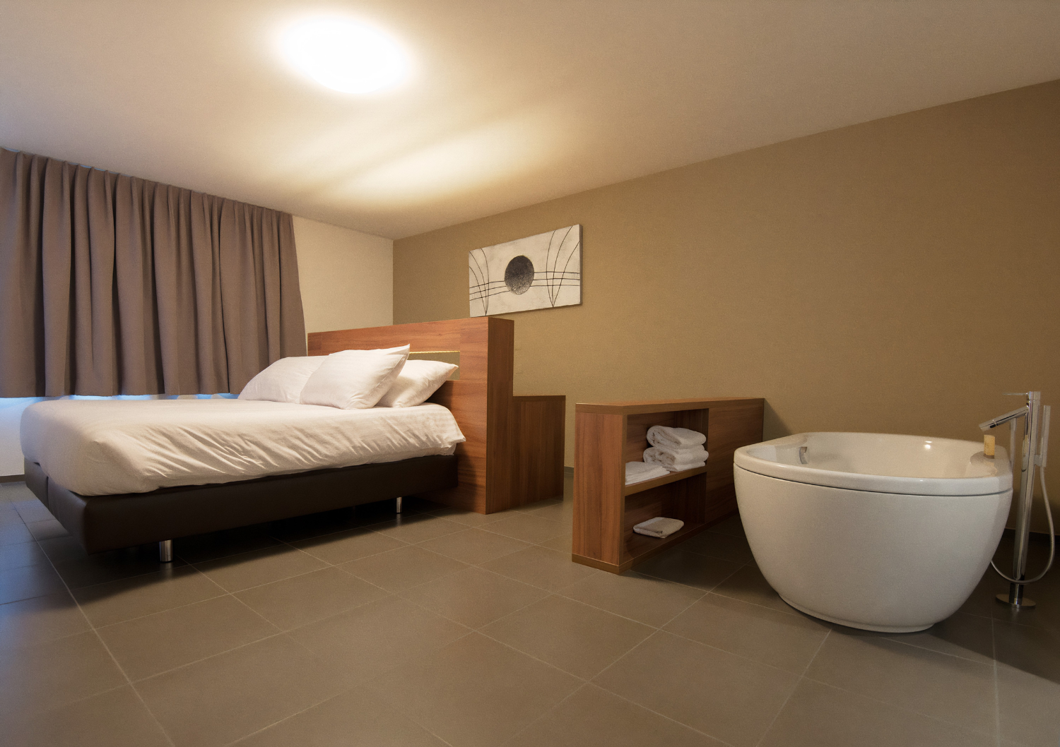 Chambre d'hôtel moderne avec lit, bureau en bois et baignoire blanche sur pieds sur sol carrelé