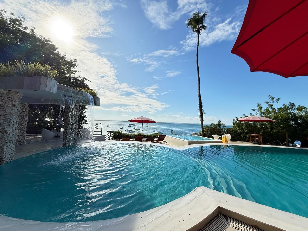 Uma grande piscina com um guarda-sol vermelho em primeiro plano Hotel Portaló
