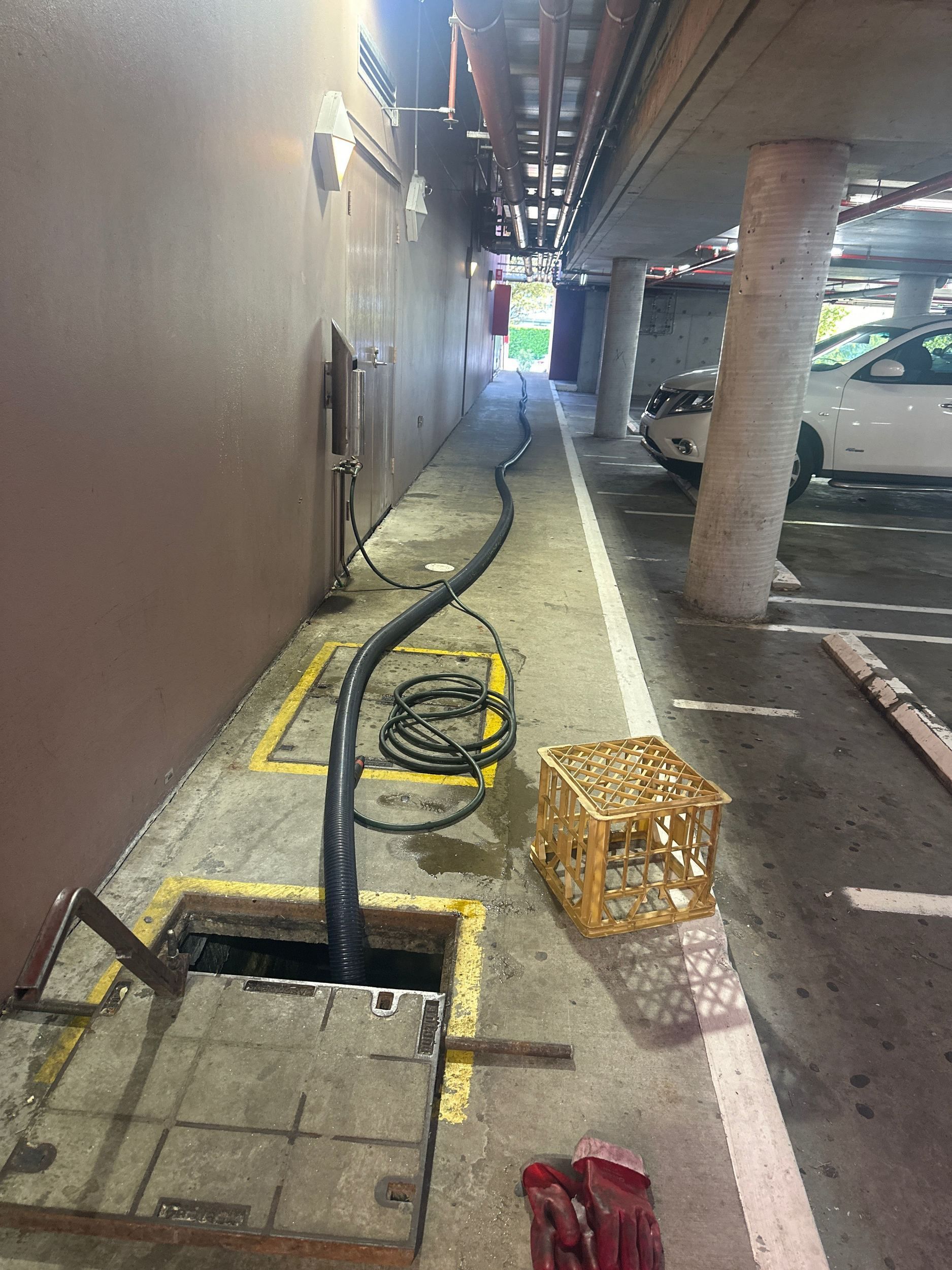 A yellow vacuum truck is parked on the side of the road in front of a building.