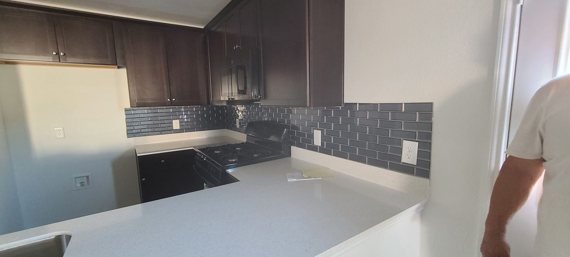 A man is standing in a kitchen with a white counter top.