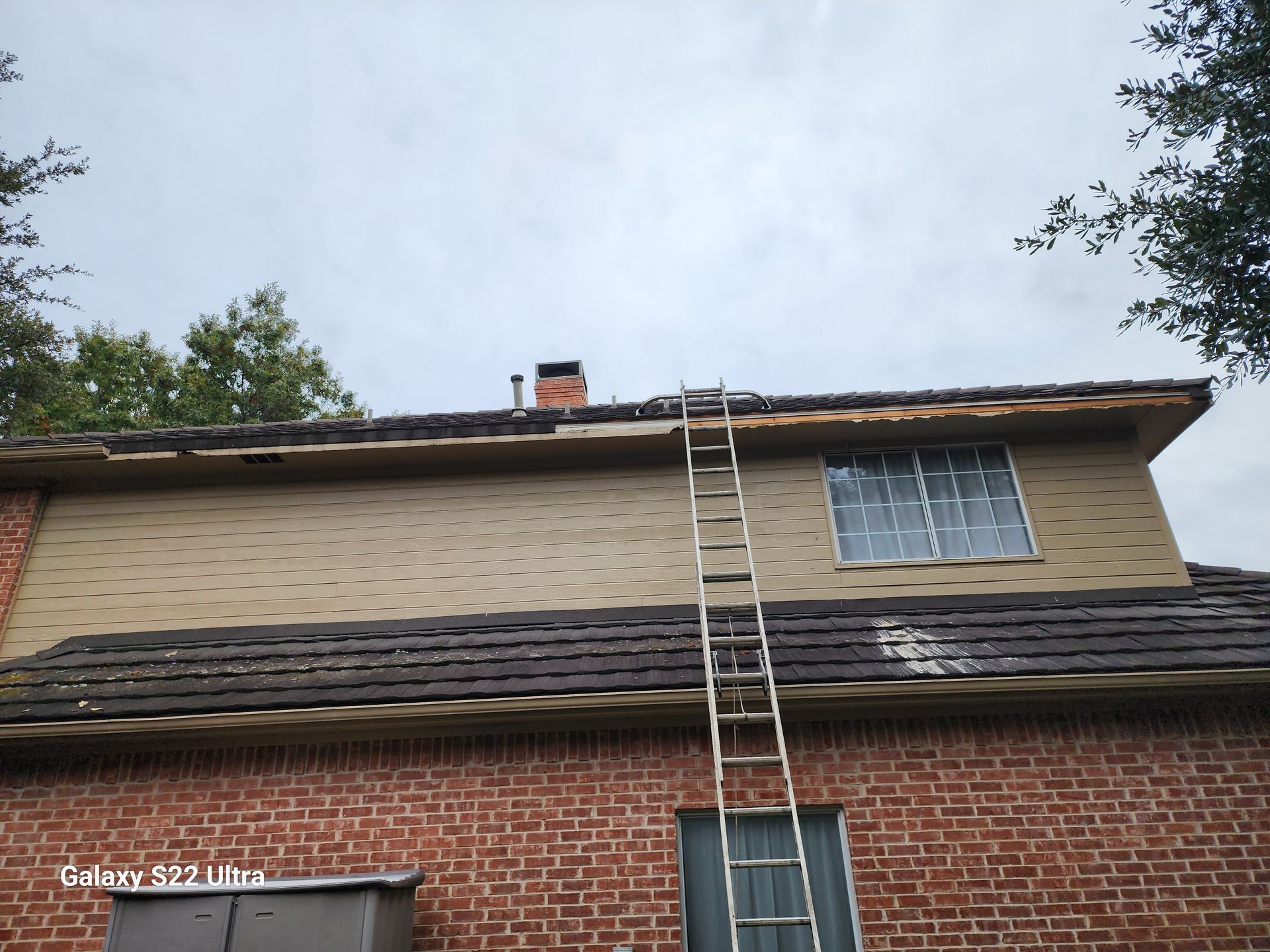 A ladder is attached to the side of a brick house.