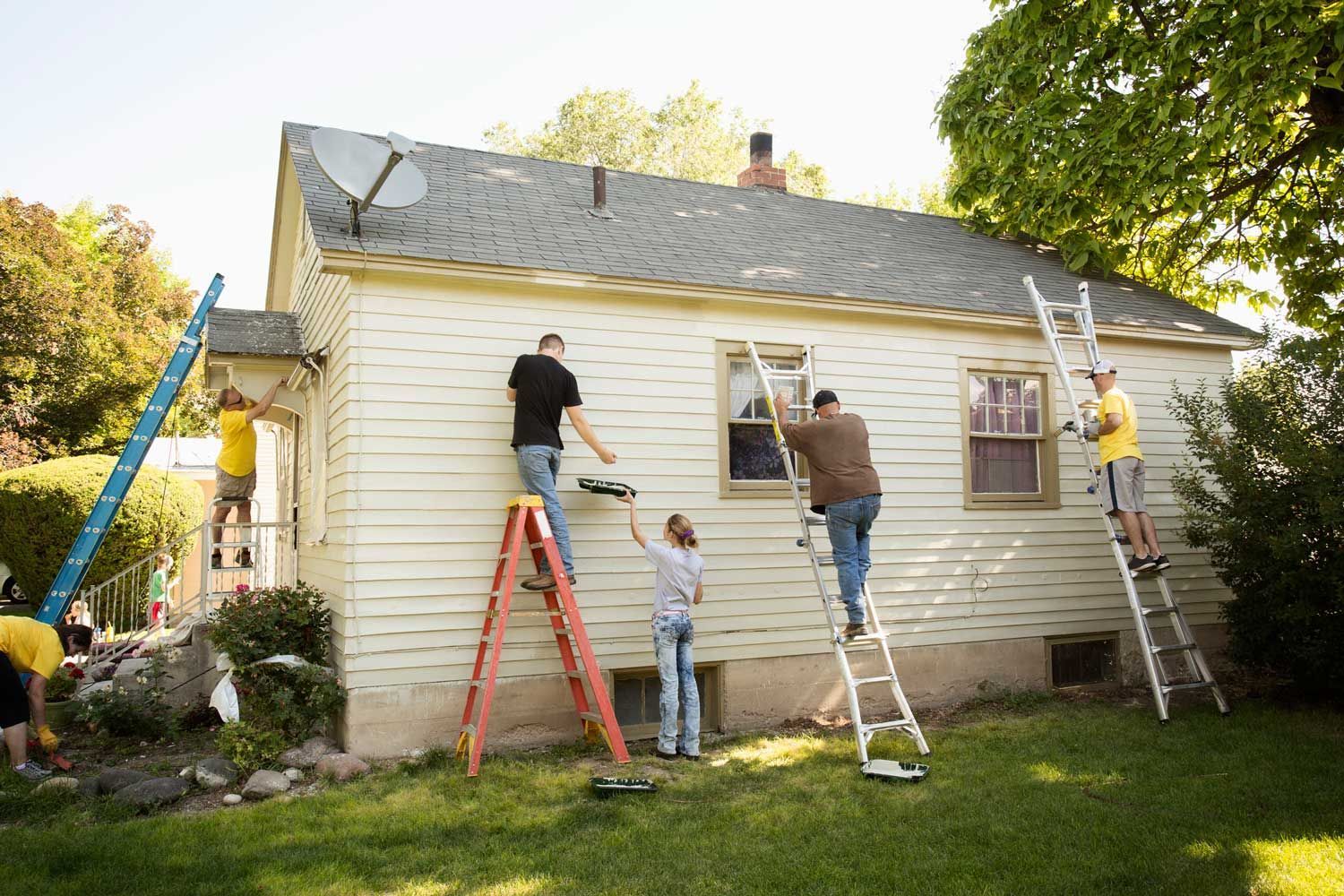 A group of people are painting the side of a house.