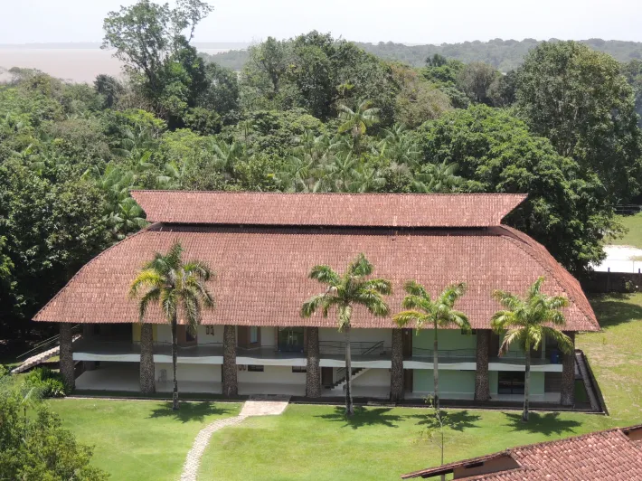 Uma casa grande com telhado de telha vermelha é cercada por árvores -HOTEL-FAZENDA-PARAISO