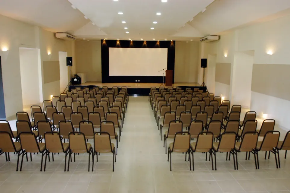 Um grande auditório com fileiras de cadeiras e uma tela grande -HOTEL-FAZENDA-PARAISO